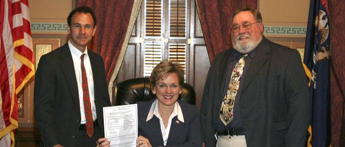 Governor Jennifer Granholm signs worker safety legislation with John DeTizio and Dale Threehouse witnessing.